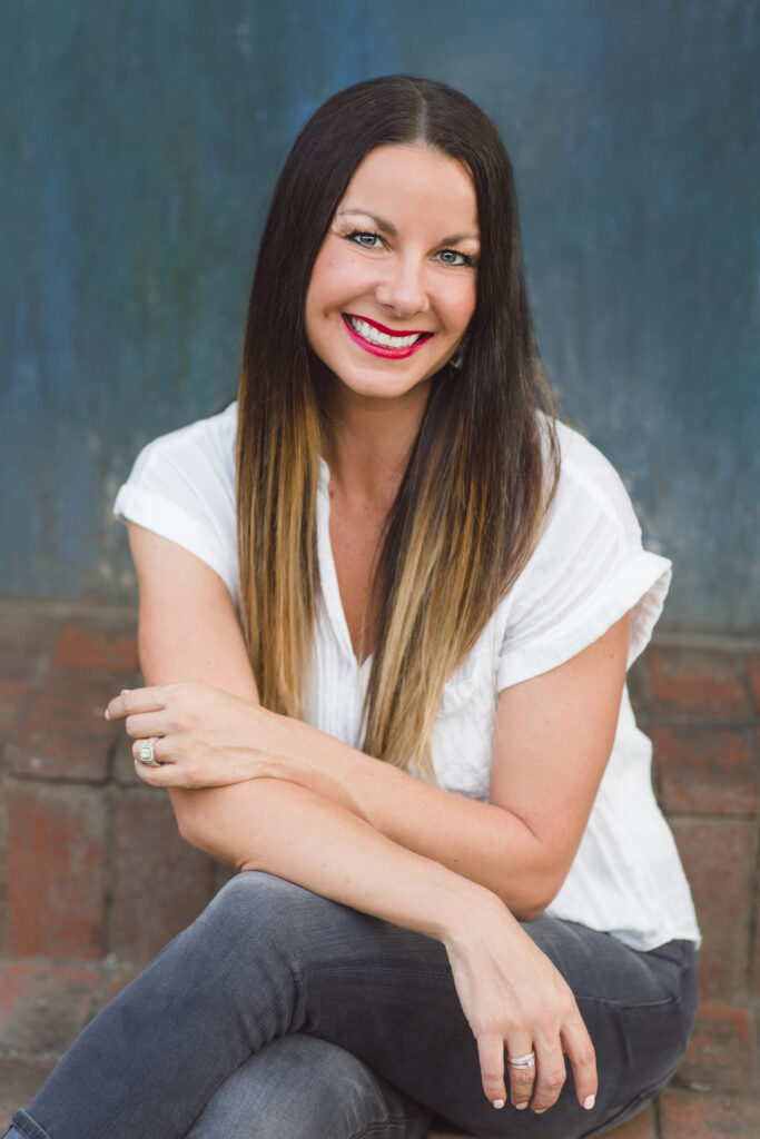 A woman in a white t-shirt and jeans sitting with her legs crossed.