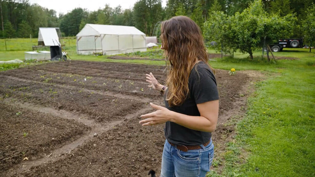 A woman standing next to a large garden bed.