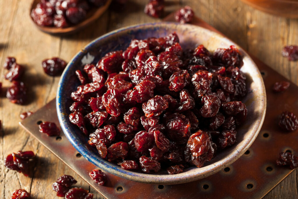 A bowl of dehydrated cherries on a wooden counter.