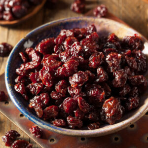 A bowl of dehydrated cherries on a wooden counter.