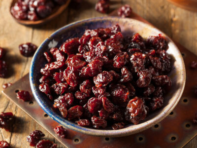 A bowl of dehydrated cherries on a wooden counter.