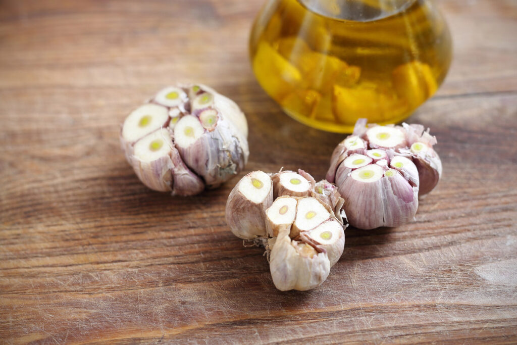 Heads of garlic next to a bottle of oil.