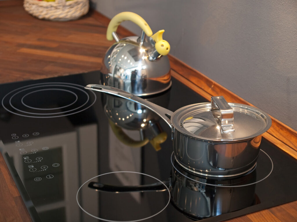 A pot and teapot on a glass stovetop.