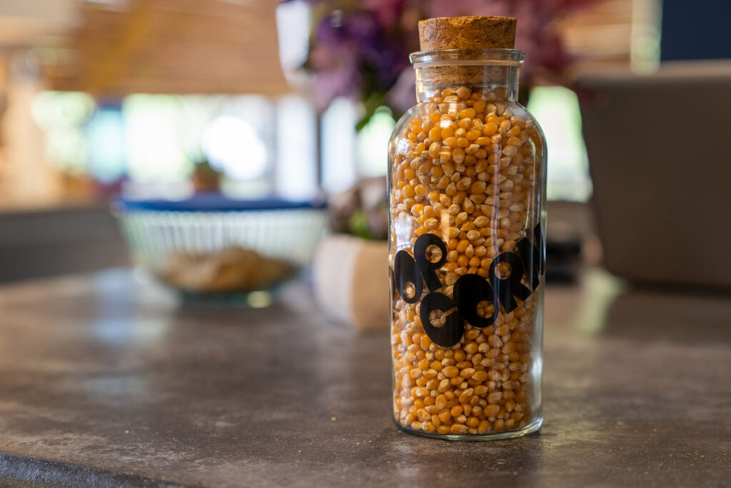 A glass bottle of popcorn kernals.