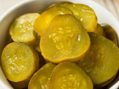 Sliced pickles in a white bowl.