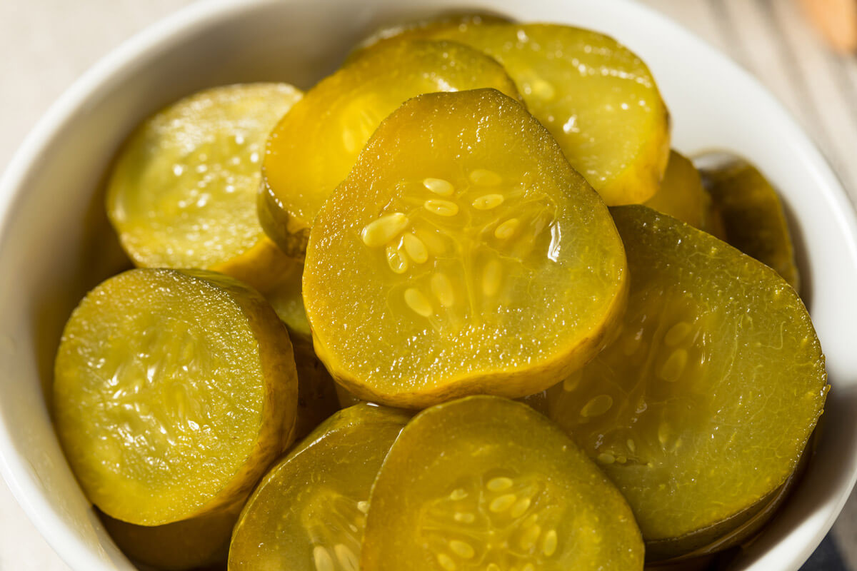 Sliced pickles in a white bowl.