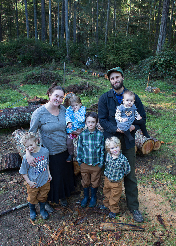 A family posing for a photo in front of the woods.