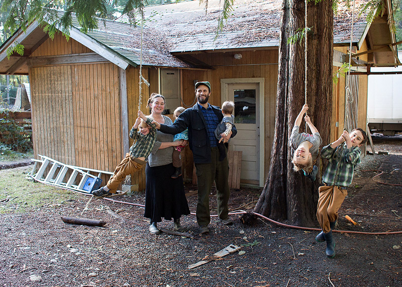 A husband and wife with their kids in front of a small house.