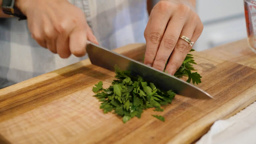 A woman chopping fresh celery leaves.