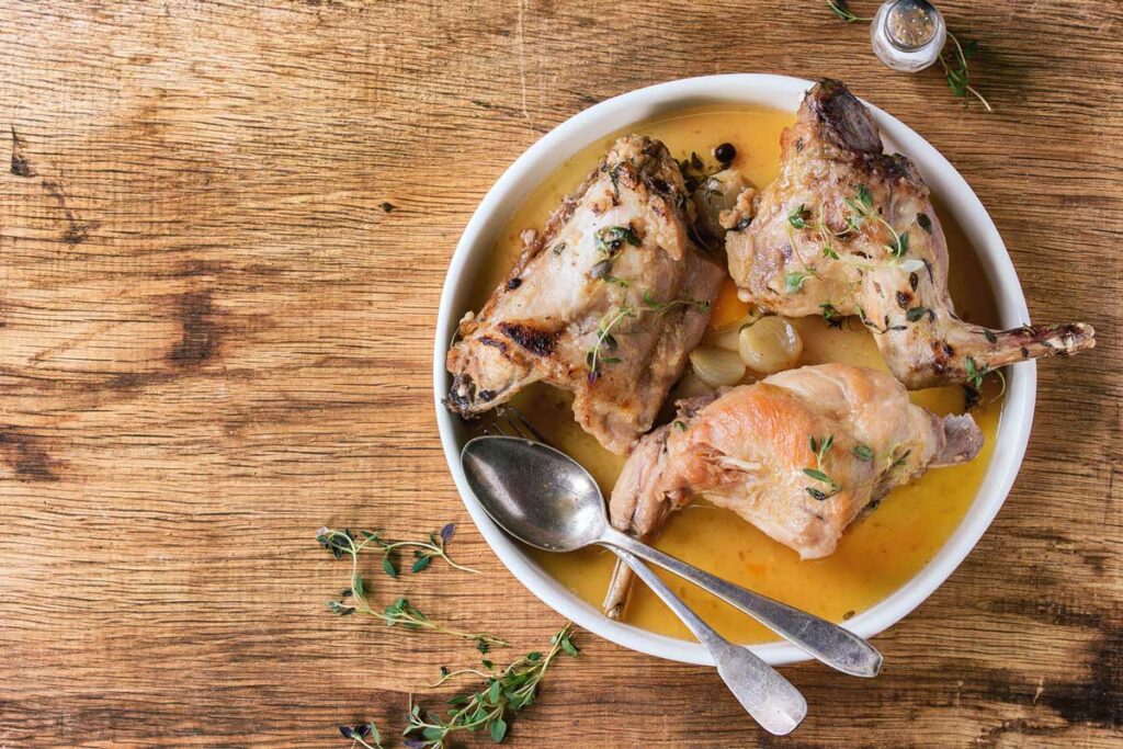 A plate with roasted rabbit and broth.