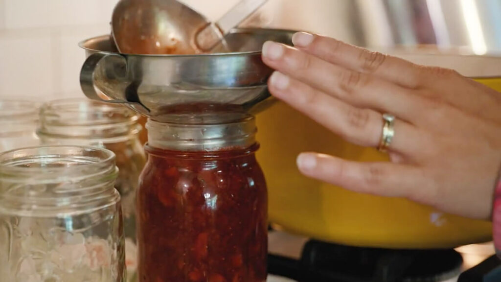 Ladling hot strawberry jam into jars.