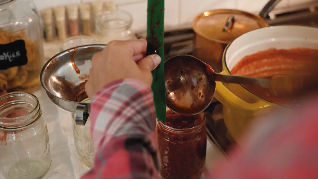 Ladling hot strawberry jam into jars.