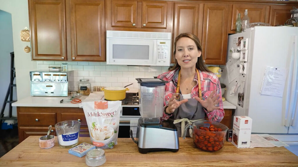 A woman in the kitchen with strawberry jam ingredients.