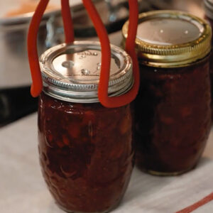 Three jars of strawberry jam hot out of the canner.