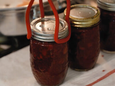 Three jars of strawberry jam hot out of the canner.