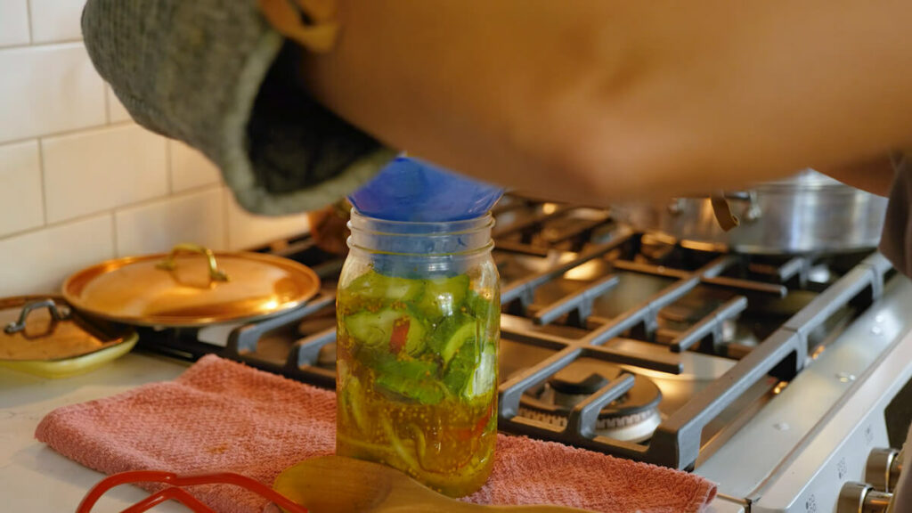 Pouring pickle brine over cucumbers.