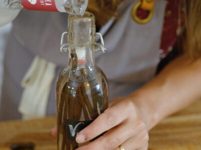 A woman pouring vodka into a bottle for homemade vanilla extract.