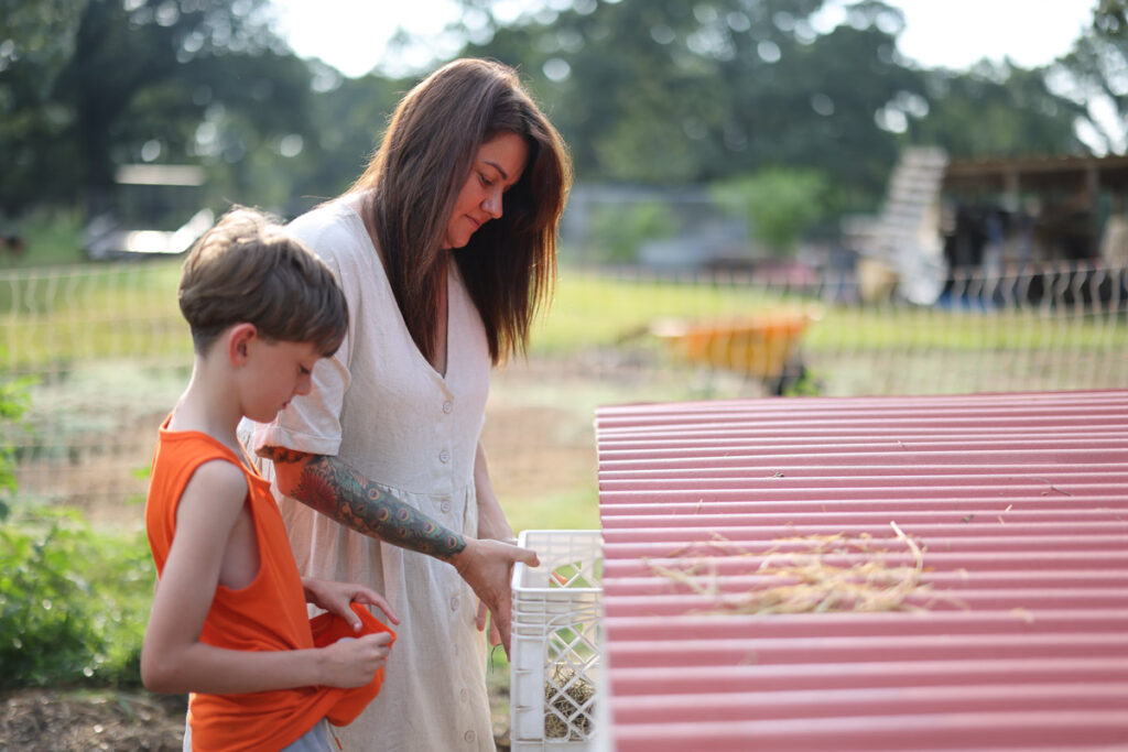 A mom and son collecting eggs from a nesting box.