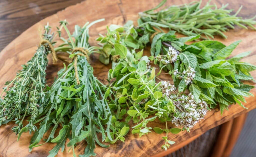 Bundles of fresh herbs laying on a wooden table.