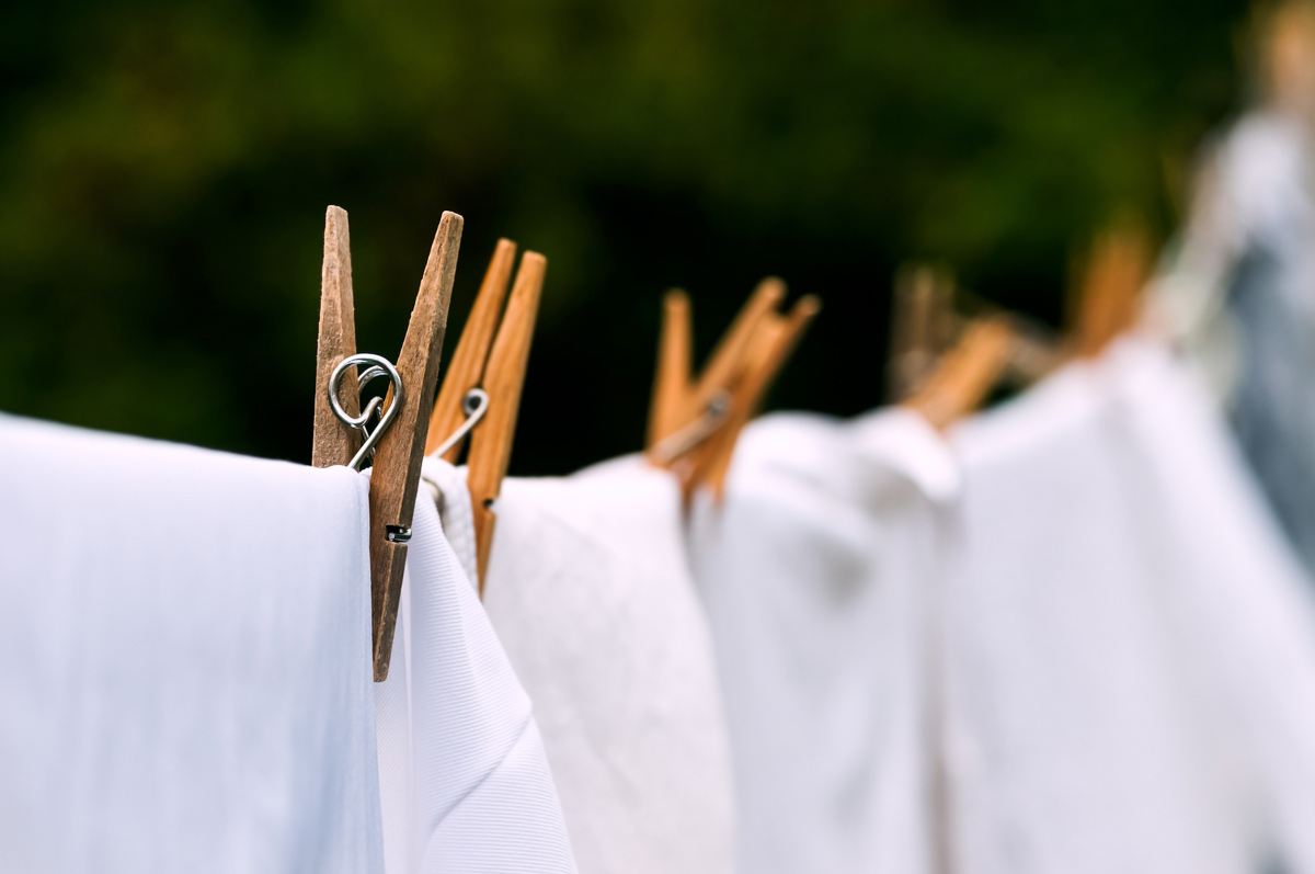 A clothesline with white sheets and clothespins.