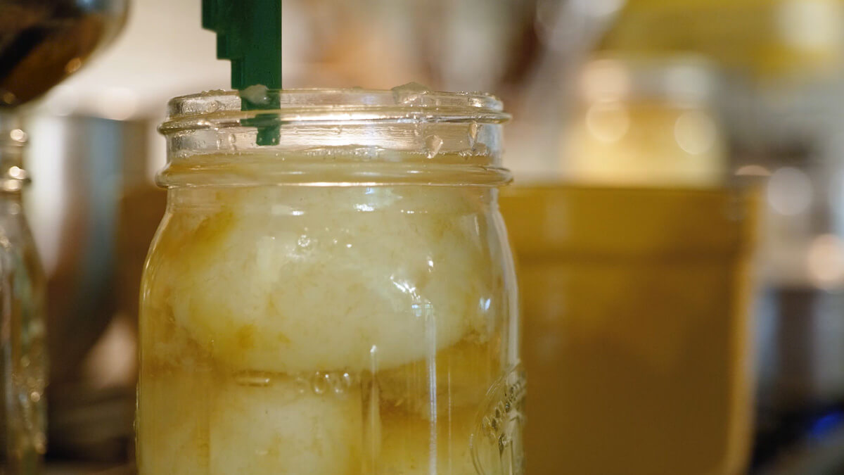 A headspace measuring tool measuring a jar of pears.