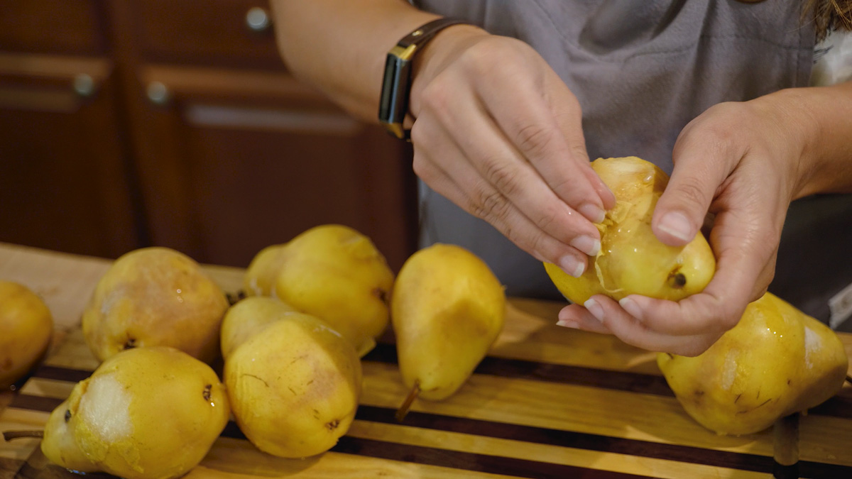 A woman peeling the skin off blanched pears.