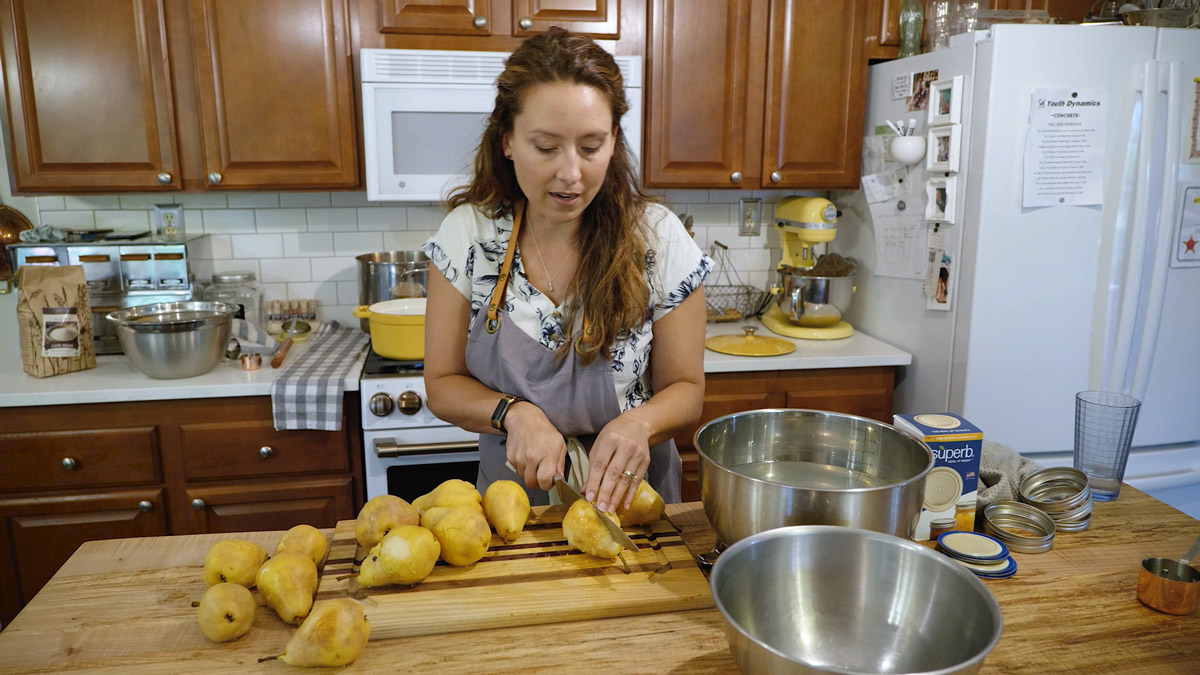A woman slicing pears in half.