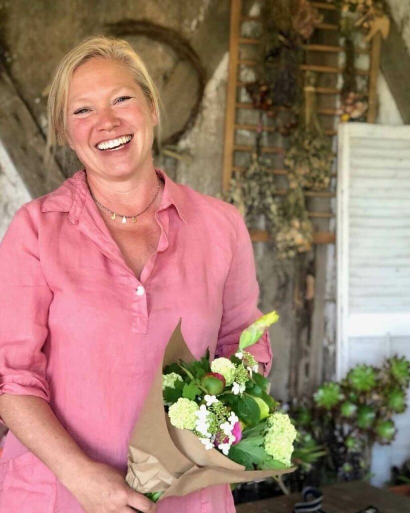 A woman smiling holding a bouquet of flowers.