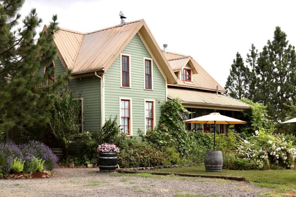 A green house with flowers and greenery.