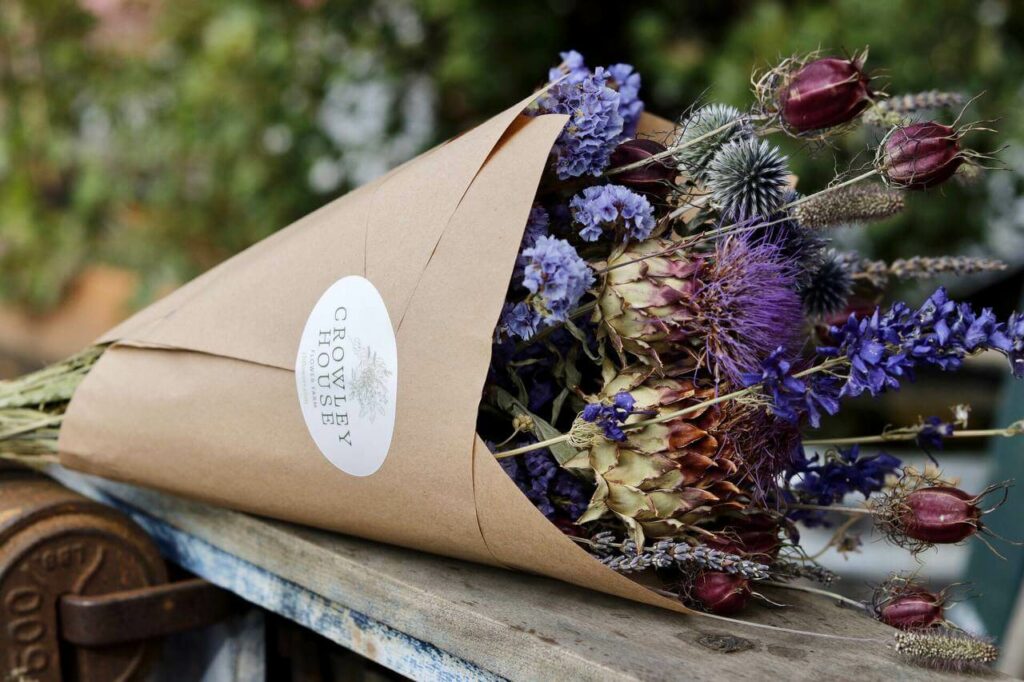 A bouquet of flowers wrapped in brown kraft paper.