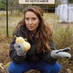 Pinterest pin for garden tasks in November. Image of a woman crouched in the garden holding a butternut squash.