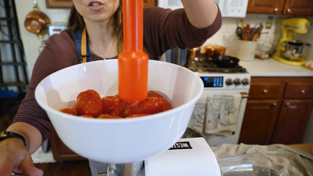 A woman pressing tomatoes through a Weston tomato press.