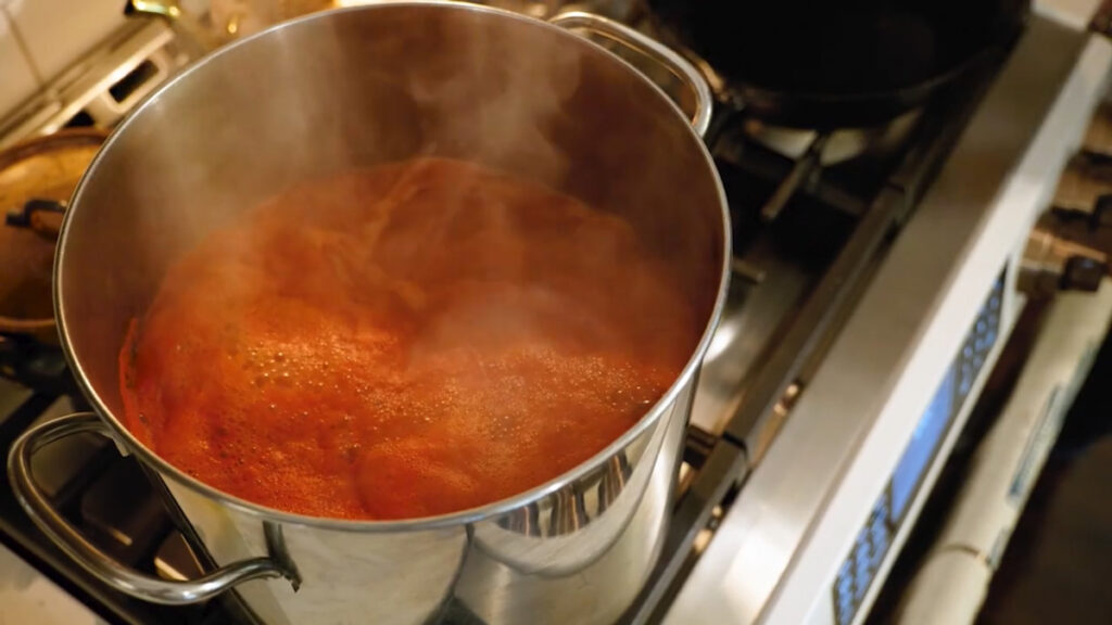 Tomato sauce being boiled and reduced on a stove.