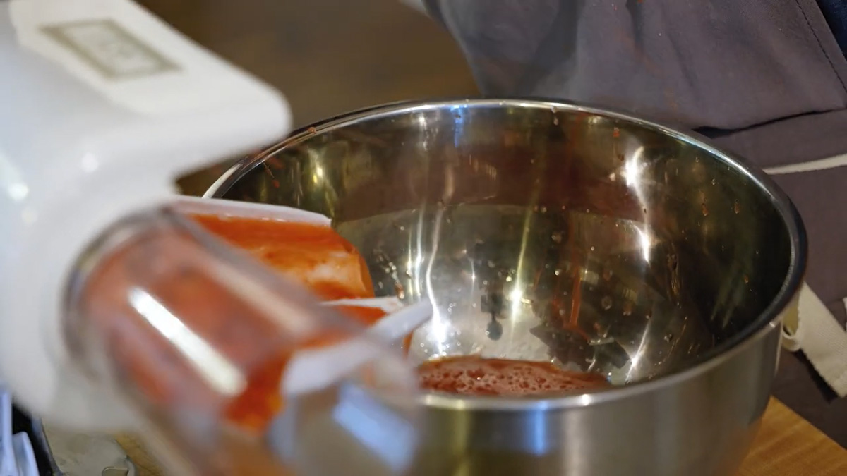 Juice from a tomato press draining into a bowl.