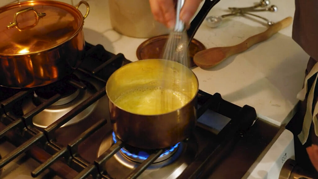 A pot of melted butter being whisked on the stove.