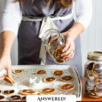 Pinterest pin for a preserving Q&A podcast. Image of a woman dehydrating orange slices.