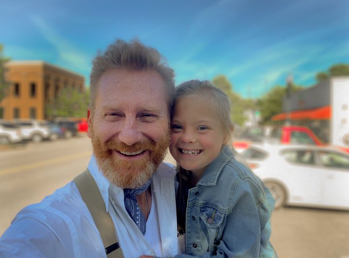 Image of a man holding his daughter with a town in the background.