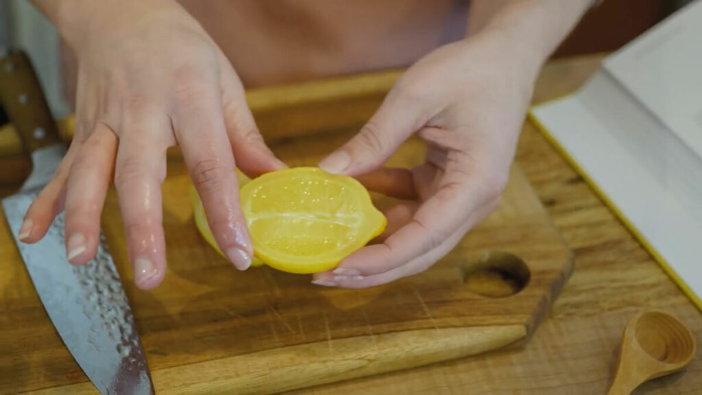 A woman holding a half a lemon.