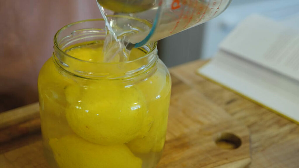 Brine being poured over lemons to ferment.