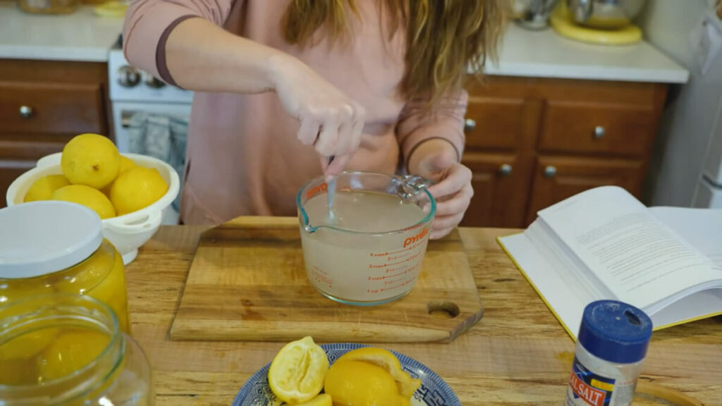 A woman stirring a saltwater brine solution in a Pyrex glass measuring bowl.