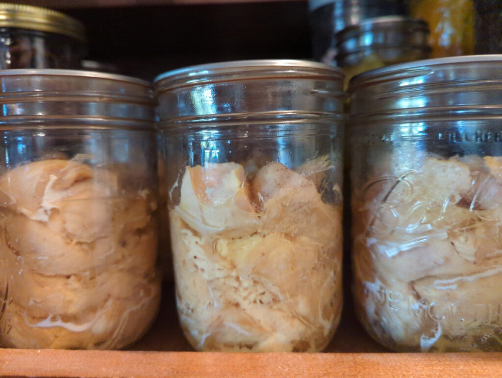 Canned chicken on a pantry shelf.