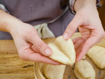 A woman's hands opening a freshly cooked bao bun.