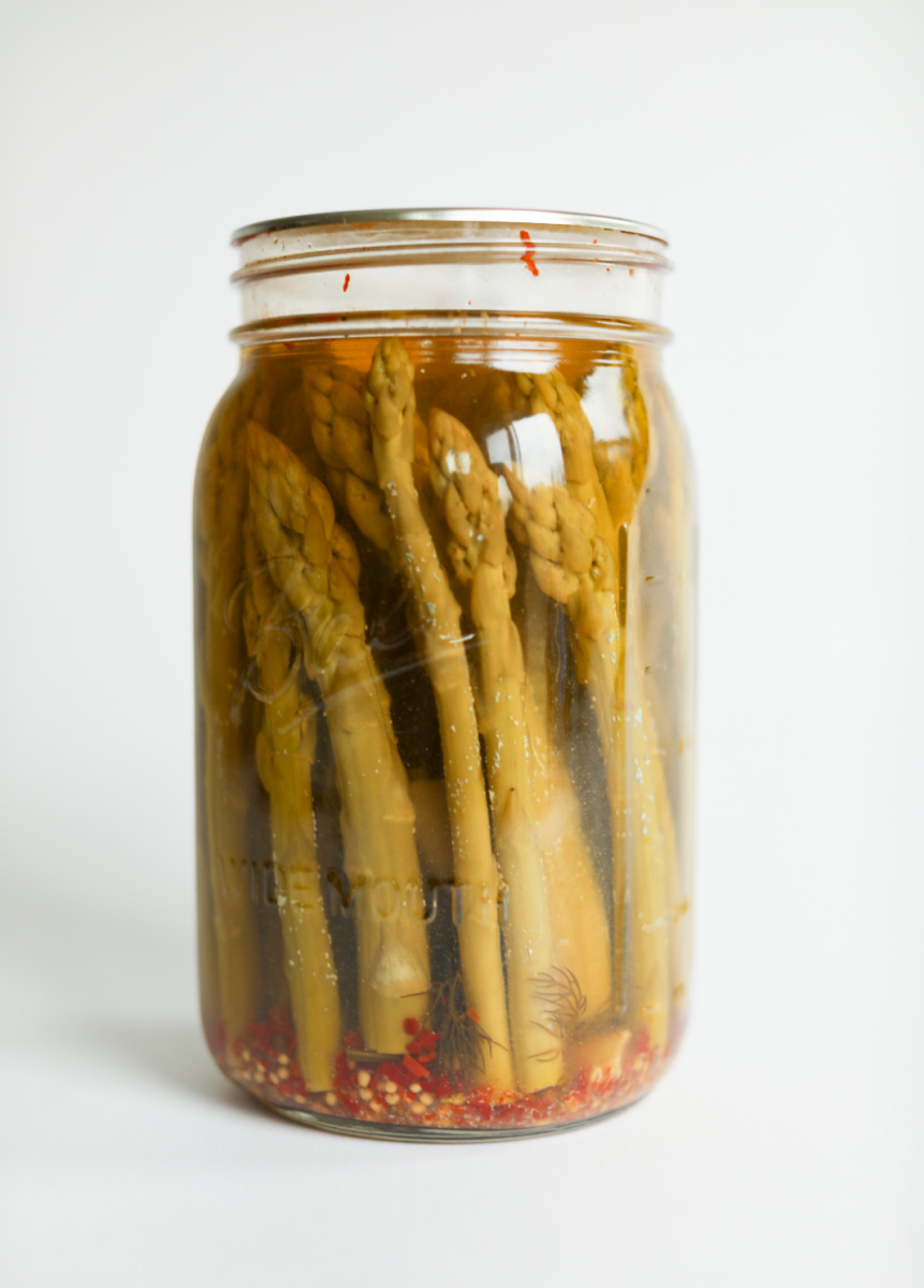 Jar of pickled asparagus on white counter