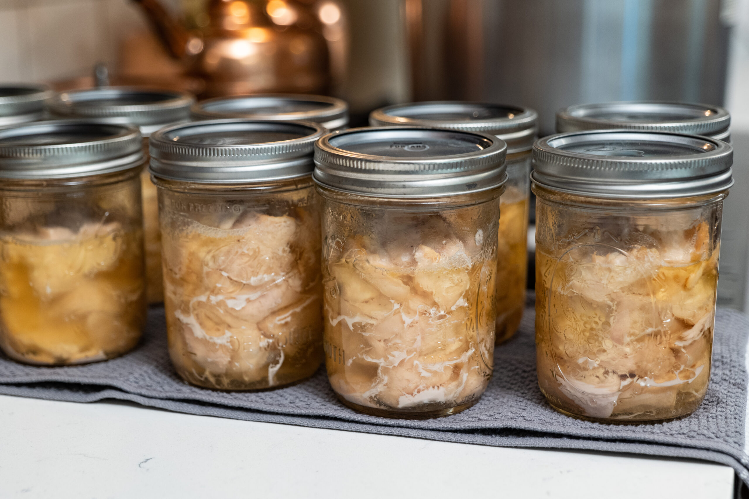 jars of canned chicken on a towel on kitchen counter