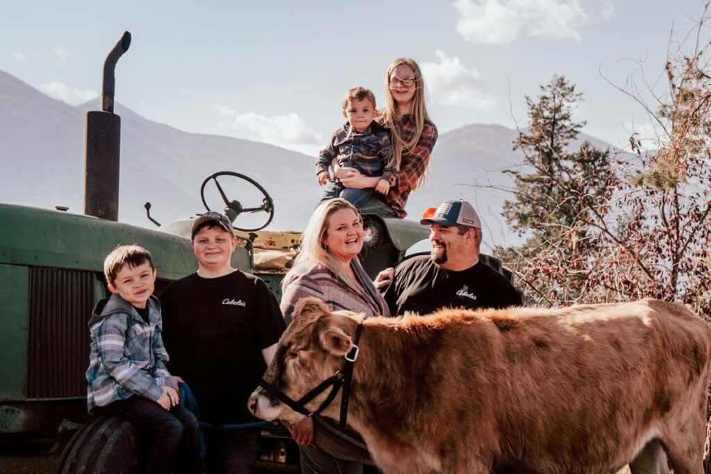 A woman and her family with a cow and a tractor.