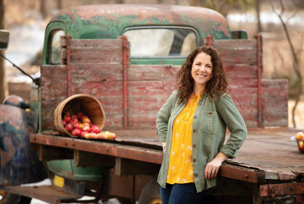 A woman leaning on an old truck.