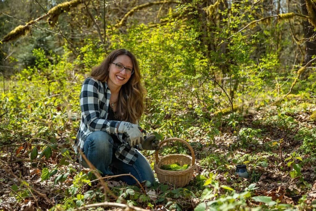 A woman foraging for stinging nettles in the forest.