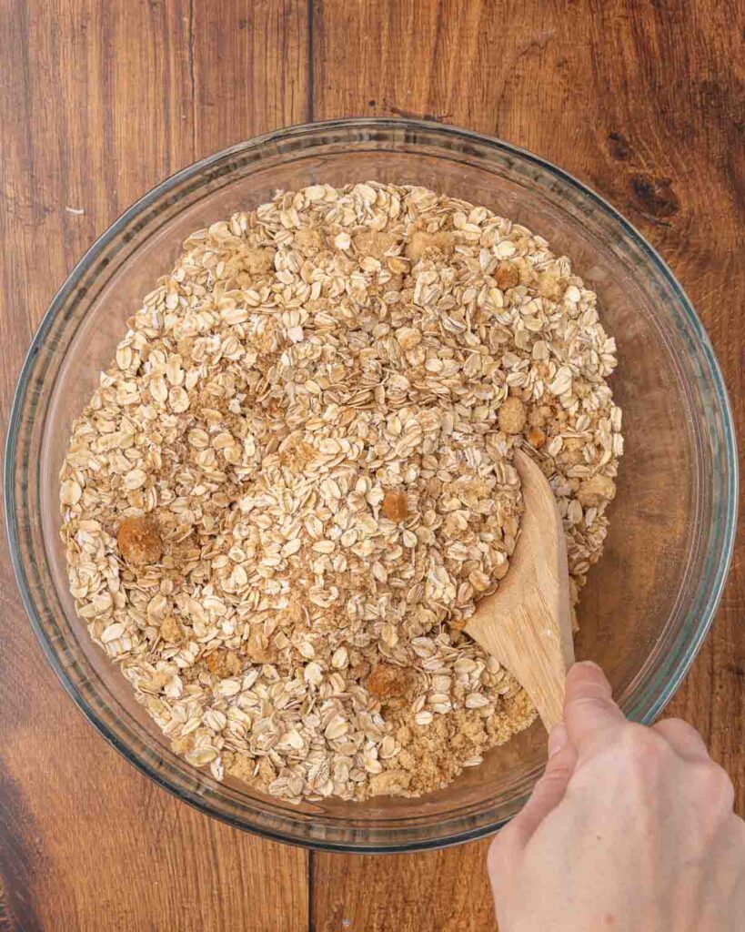 A glass bowl with a wooden spoon stirring instant oatmeal mix together.