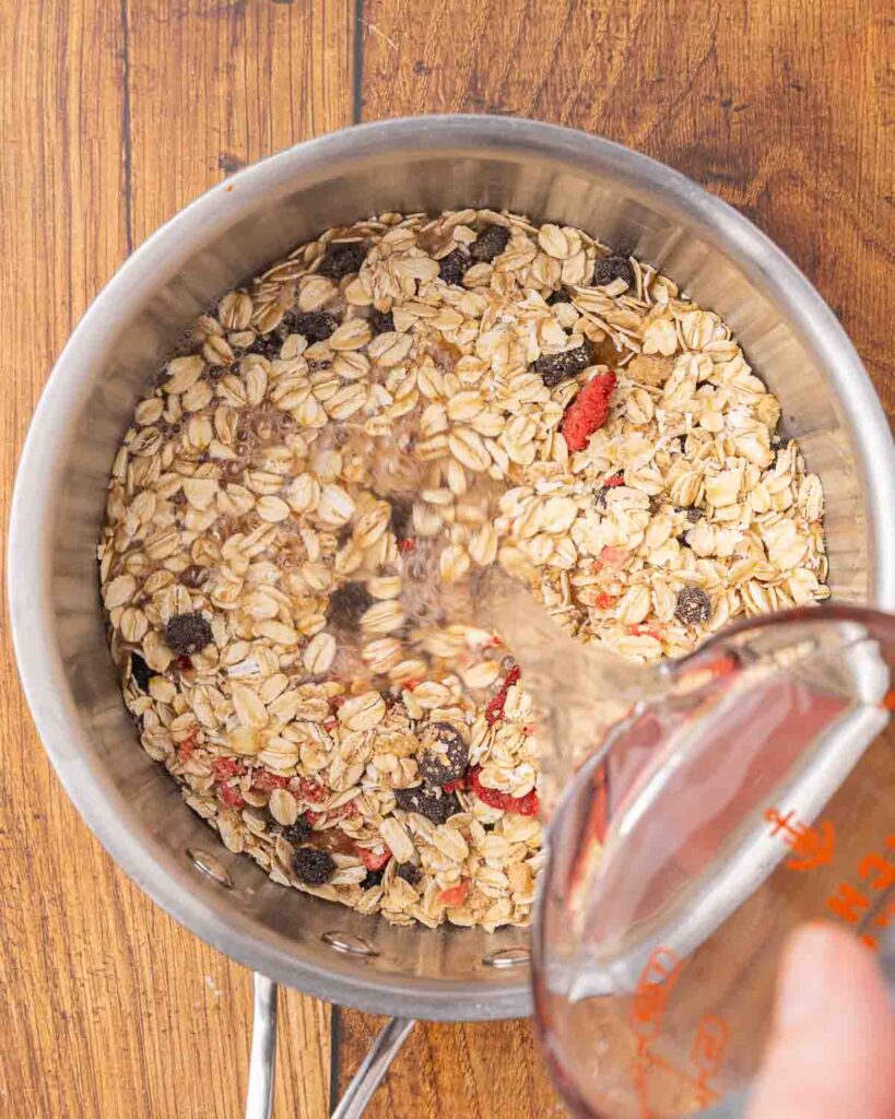 Adding water to a saucepan with instant oatmeal mix.