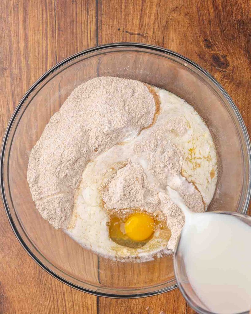 Adding wet ingredients to dry muffin ingredients in a bowl.